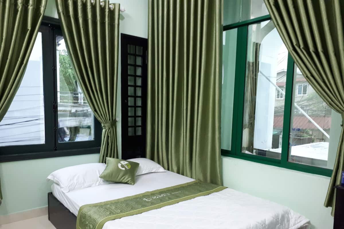 Una habitación con una cama, cortinas, una ventana y una puerta.