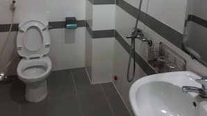 Et badeværelse med toilet, vask og brusebad.