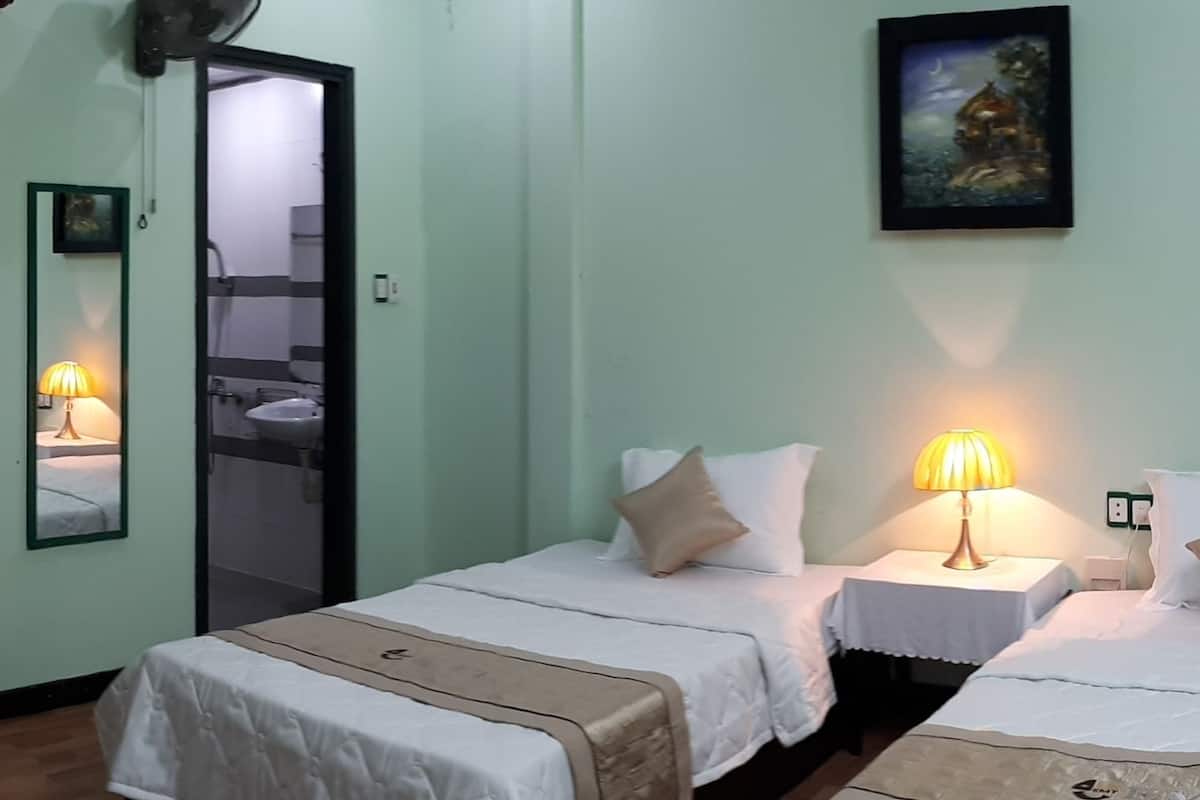 Habitación de hotel con dos camas, una lámpara de noche, un espejo y un cuadro en la pared.