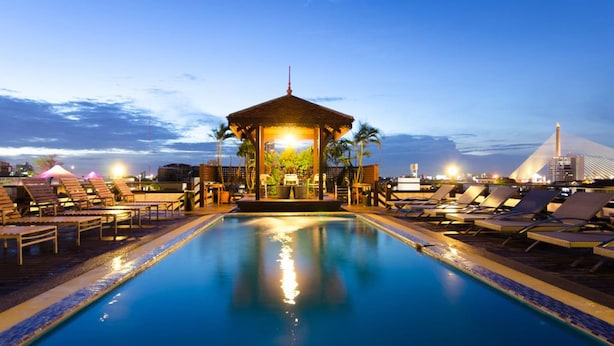Uma área de piscina com espreguiçadeiras e um gazebo ao anoitecer.