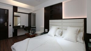 Una habitación de hotel moderna con una cama grande, una mesita de noche, un espejo y un ventilador de techo.