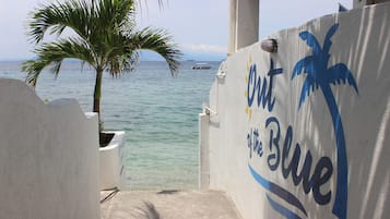 Uitzicht op de zee vanaf een balkon met een palmboom en een bordje waarop 'Out of the Blue' staat.