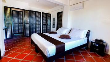 A bedroom with a bed, a nightstand, and a red-tiled floor.
