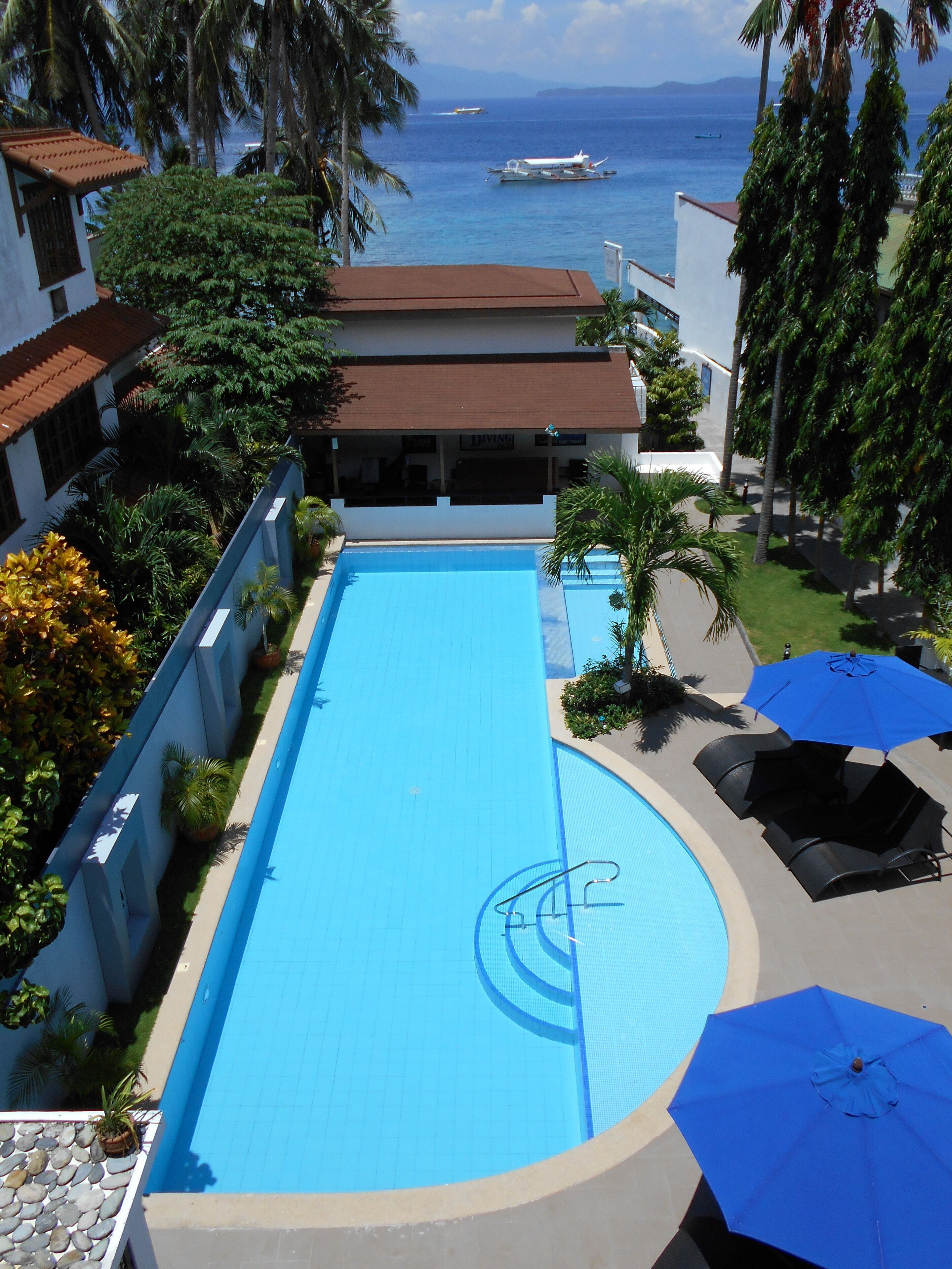 Una piscina con vista al mar, rodeada de palmeras y un edificio con un letrero que dice "LIVING".