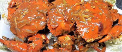 A plate of cooked crabs with a glossy sauce, served on a white plate with lettuce leaves.