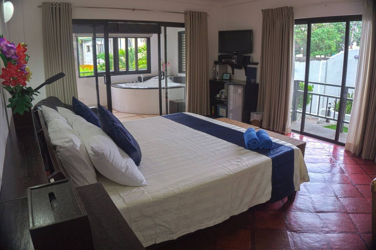 Een hotelkamer met een bed, een bureau, een televisie en uitzicht op buiten.