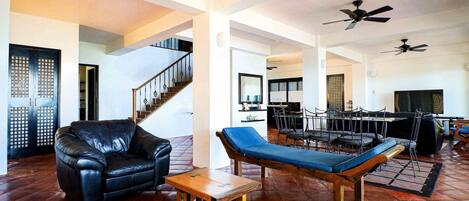 A spacious living area with a leather sofa, a wooden coffee table, and a blue cushioned bench. A staircase with a railing leads to another level.