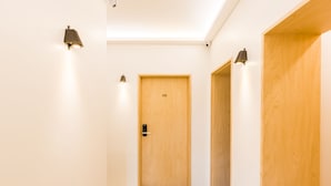 A hallway with a wooden door labeled "C02", a light fixture on the wall, and a wooden panel on the right. - BAROATO 2nd (Seoul)