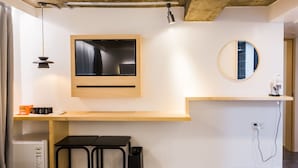 A modern kitchenette with a built-in oven, a small refrigerator, a black table, and a stool. - BAROATO 2nd (Seoul)
