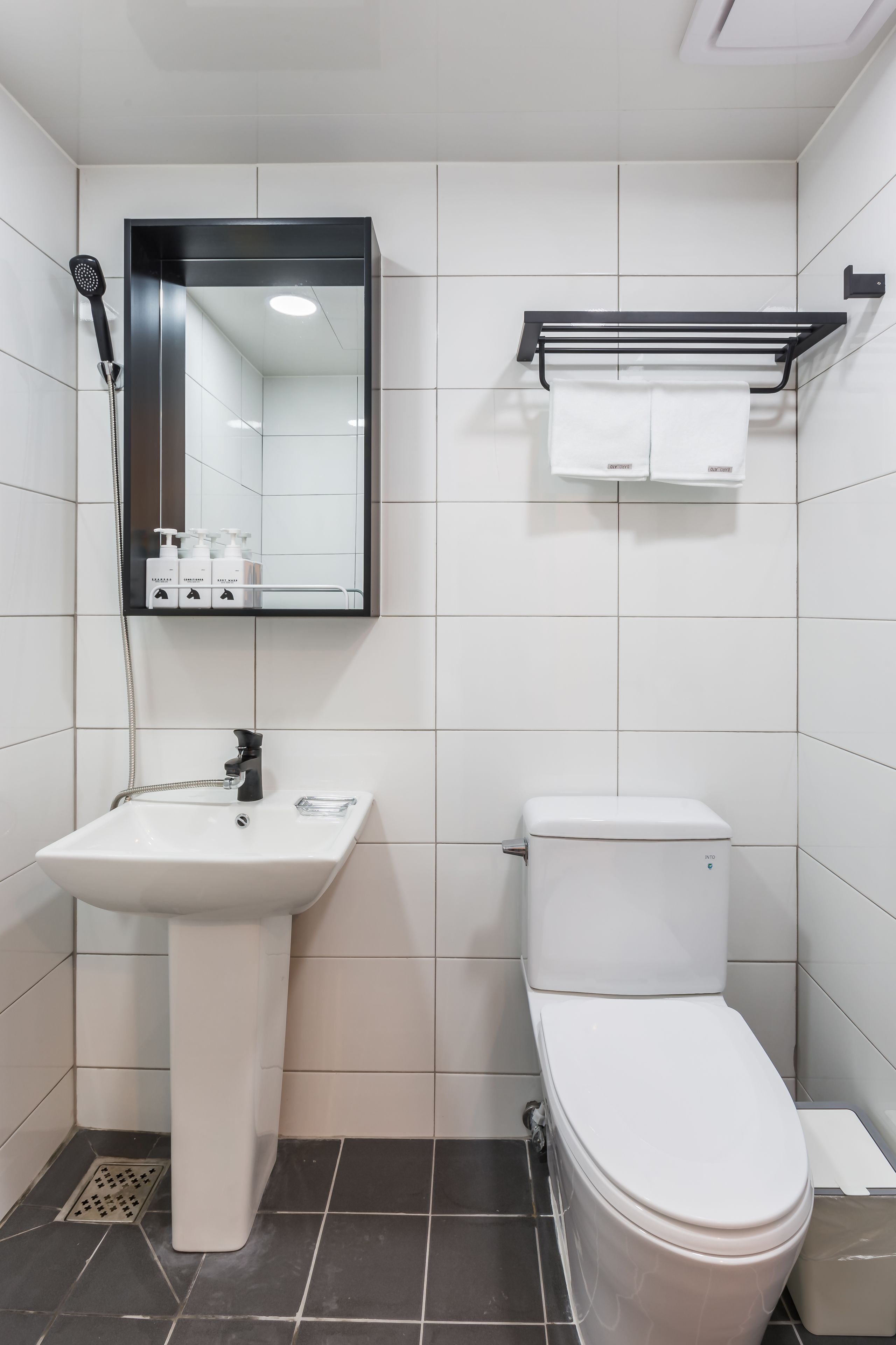 A modern bathroom with a white sink, a toilet, and a mirror above the sink.