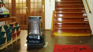 Ein Zimmer mit Holzboden, einer schwarzen Mülltonne, einer roten Matte und einer Treppe mit hölzernen Stufen.