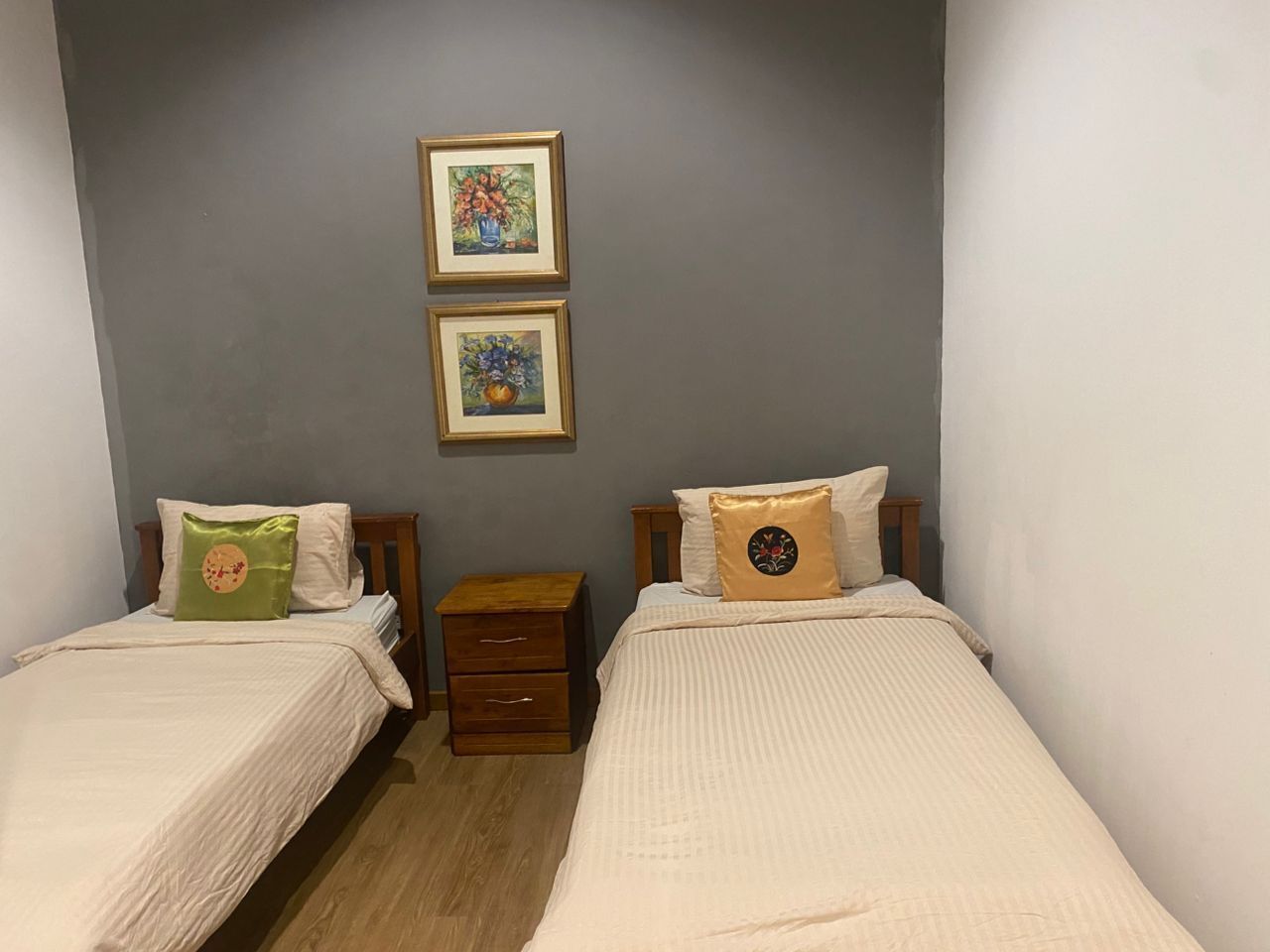 Une chambre à coucher avec deux lits, chacun étant équipé d’un oreiller et d’une petite table de chevet en bois.