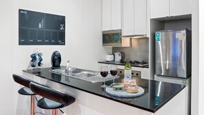 Una cocina moderna con encimera negra, electrodomésticos de acero inoxidable y una zona de bar con dos taburetes.