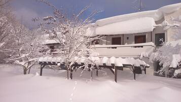 A snow-covered building with a balcony and a wooden table in front.