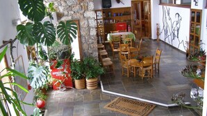 Un espace repas avec un sol en pierre, des chaises en bois et une table recouverte d’une nappe verte.