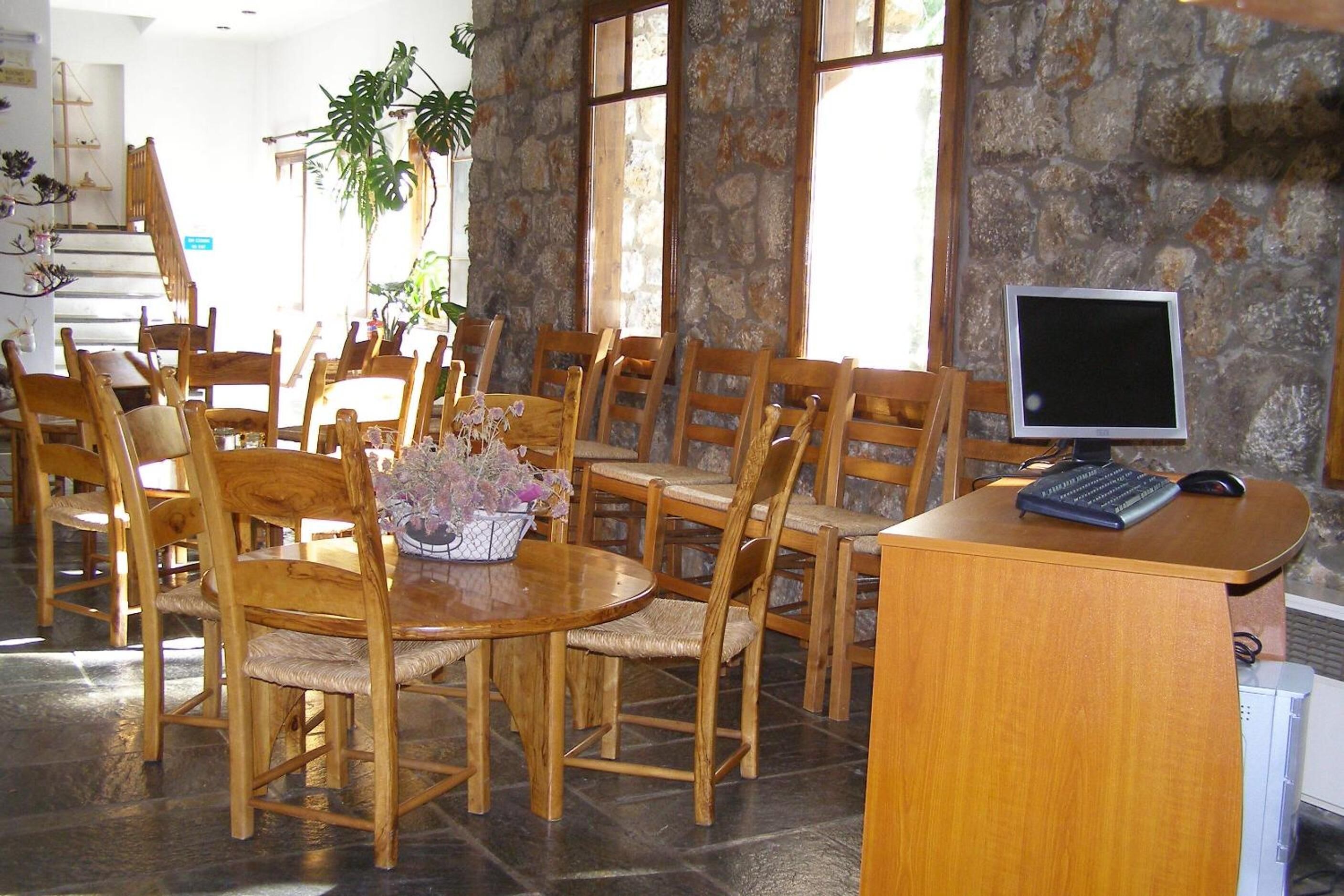 Une salle de conférence avec une table ronde en bois, plusieurs chaises, une petite plante et un ordinateur posé sur un bureau.