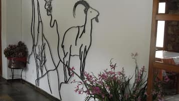 A wall with a line drawing of a goat and a human profile. There are potted plants on the floor.