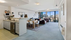 Een modern appartement met keuken, eethoek en woonkamer met groot raam en uitzicht over de stad.