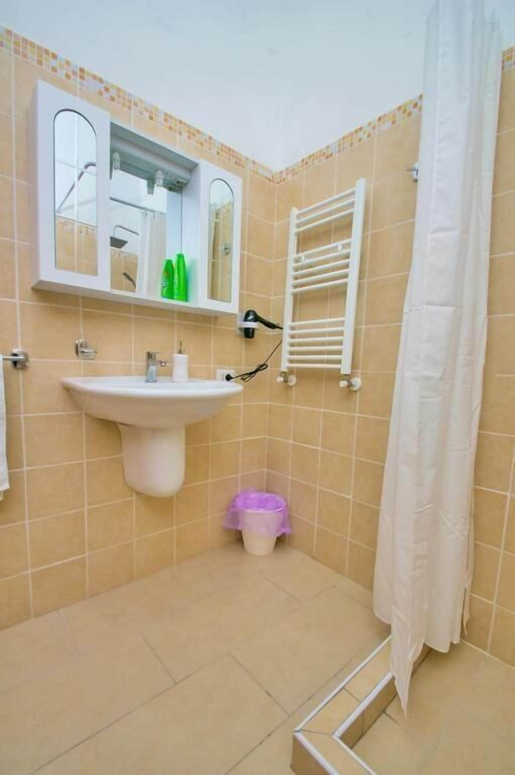 A bathroom with a pedestal sink, a mirror, a towel rack, and a shower curtain.