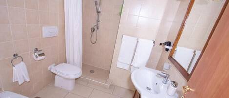 Un baño con inodoro, bidé, lavabo y ducha.