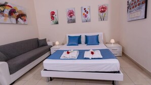 Una habitación de hotel con cama, sofá y obras de arte en las paredes.