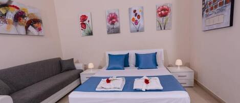 A hotel room with a bed, a sofa, and artwork on the walls.