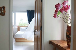 Une chambre à coucher avec un lit, une porte en bois et un vase rempli de fleurs.