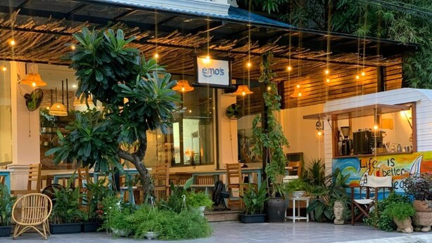 A restaurant with a rustic wooden ceiling, hanging lights, and a sign reading "emo's".
