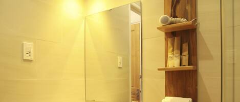 Un baño con un lavabo blanco, un espejo, un perchero para toallas y un estante con artículos de aseo.