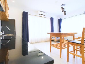 A modern kitchen with a built-in stove, a sink, and a window with curtains. There is a wooden dining table with chairs.