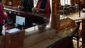 Un espace d’accueil avec un décor intérieur en bois, un comptoir en verre et un ventilateur de plafond.