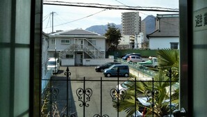 Un quartier résidentiel avec une maison blanche, des voitures garées et une montagne en arrière-plan.