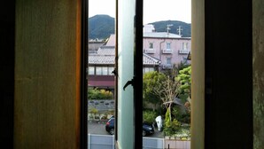 Une vue à travers une porte entrouverte, révélant un bâtiment avec un toit en tuiles et une montagne en arrière-plan.