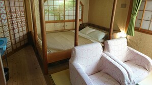 Une pièce de style japonais traditionnel, avec un sol recouvert de tatamis, un futon servant de lit, une tête de lit en bois et un paravent shoji.