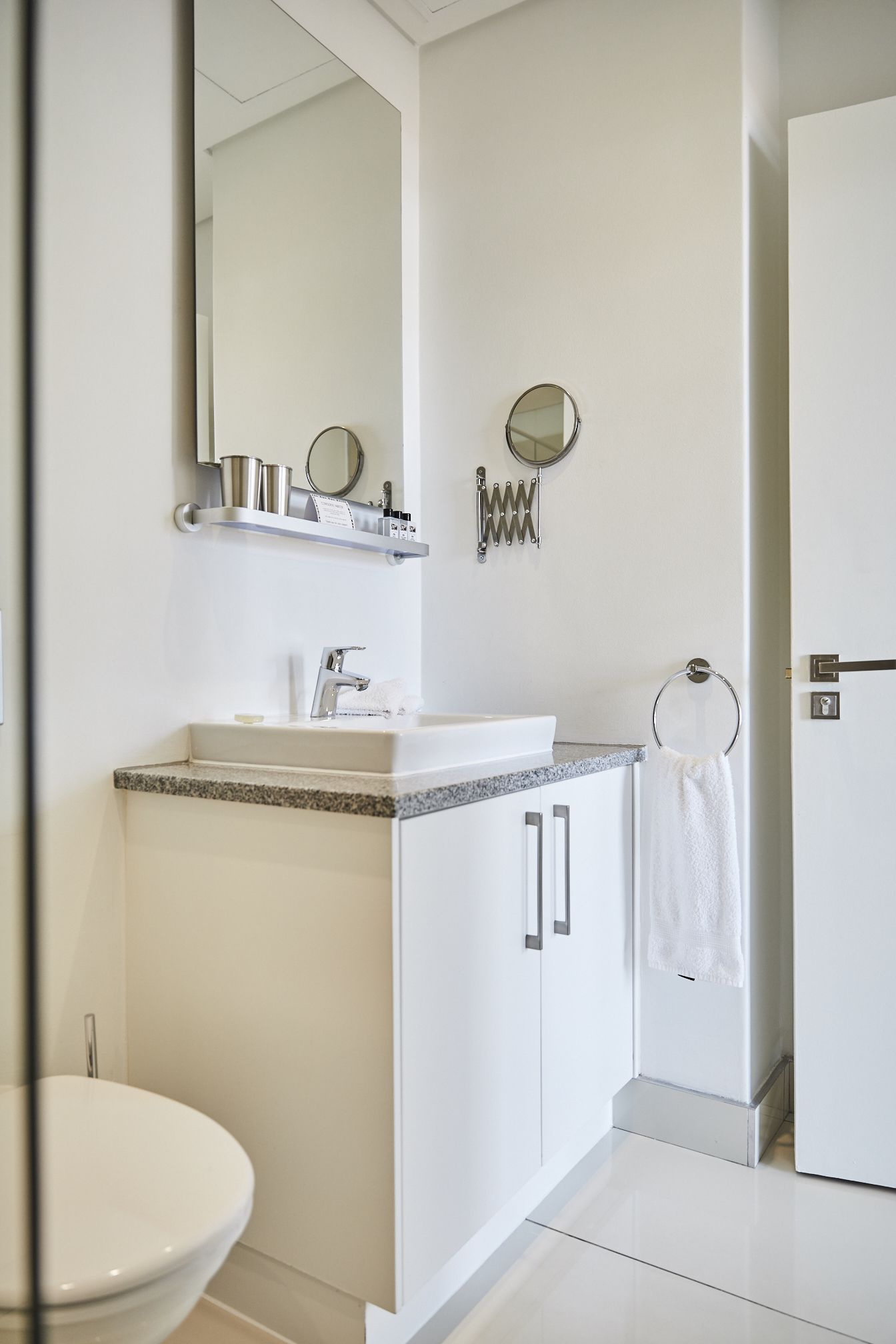 A modern bathroom with a white sink, mirror, and toilet.