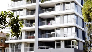 Un immeuble à plusieurs étages, doté de balcons, d’un rez-de-chaussée en pierre et d’une enseigne indiquant « L’Odyssée ».