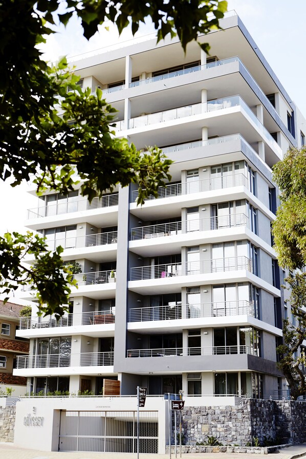 A multi-story building with balconies, a stone base, and a sign indicating "The Odyssey."