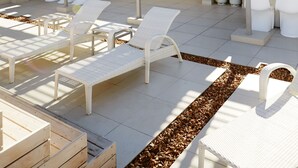 Une terrasse sur le toit, dotée de meubles en osier blanc, d’un barbecue et offrant une vue sur la mer.