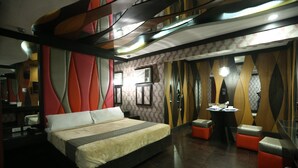 A modern hotel room with a large bed, a desk, and a seating area. - Victoria Court Canley - Pasig (Pasig)