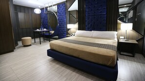 A modern hotel room with a large bed, a desk, and a chair. - Victoria Court Canley - Pasig (Pasig)