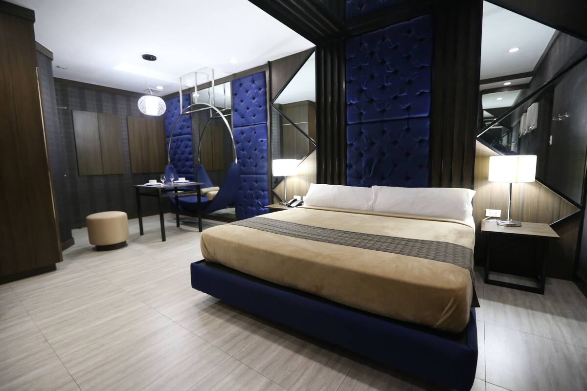 A modern hotel room with a large bed, a desk, and a chair.