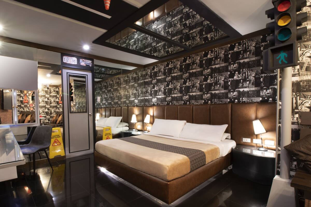 A hotel room with a bed, bedside tables, a desk, and a chair.