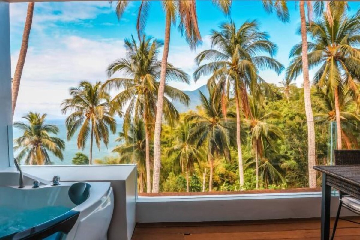 A room with a large window overlooking palm trees and a view of the ocean.