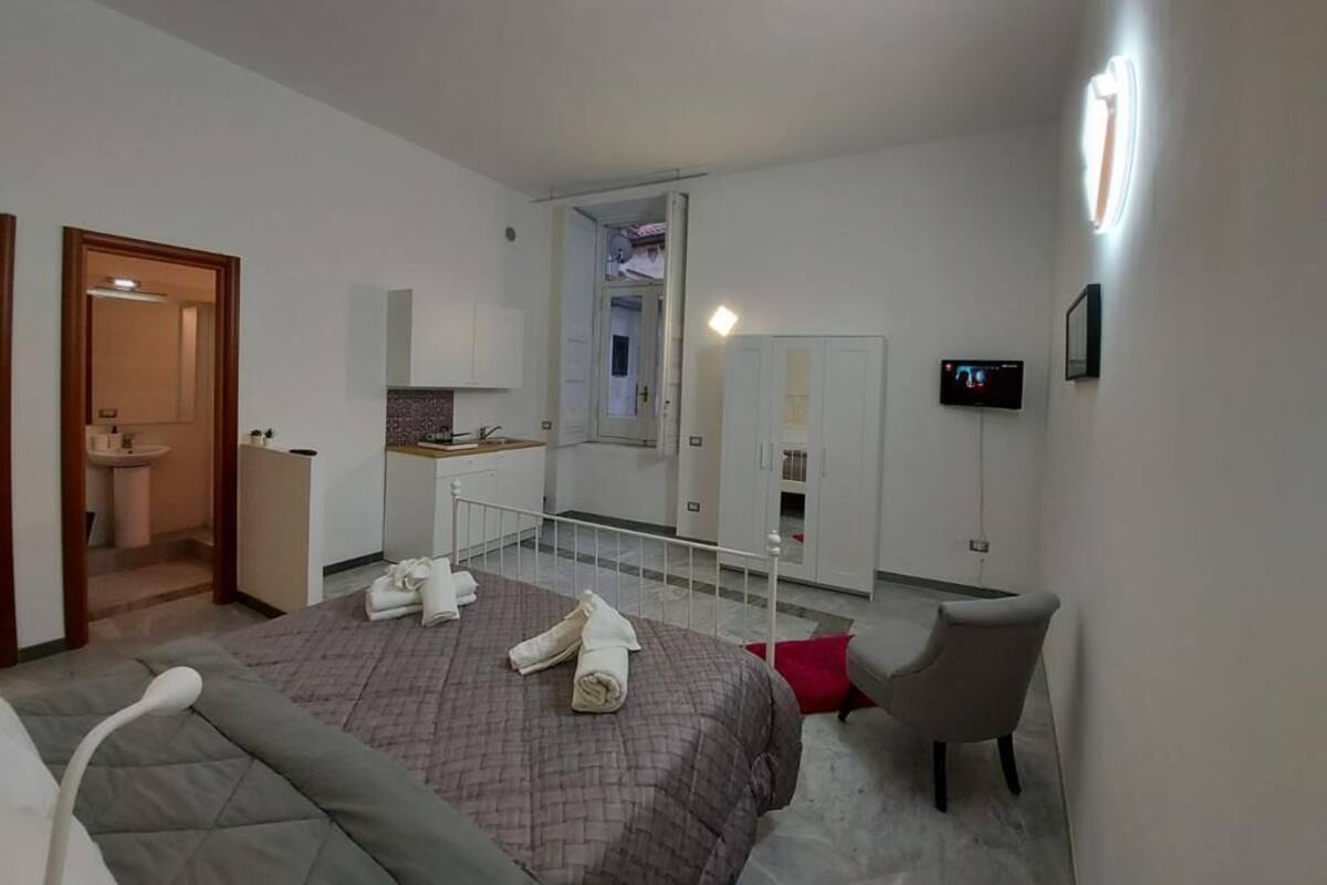 Una habitación de hotel moderna con cama, escritorio, silla, televisión y baño visible a través de una puerta abierta.