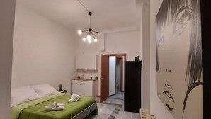 Une chambre d’hôtel moderne, équipée d’un lit, d’un petit bureau, d’un radiateur et d’un tableau au mur.
