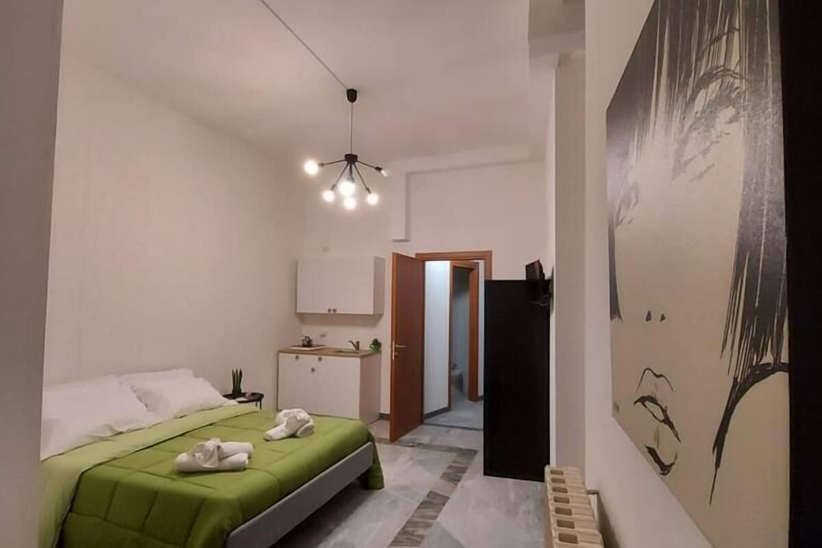 Una habitación de hotel moderna con una cama, un escritorio pequeño, un radiador y un cuadro en la pared.