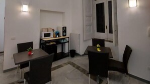 Un espace de vie compact comprenant un coin repas, une kitchenette et une fenêtre avec des rideaux.