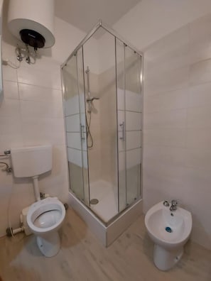 Un baño con ducha acristalada, inodoro y bidé.