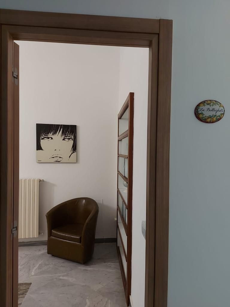 A doorway leading to a room with a radiator, a brown chair, and a wall-mounted picture.
