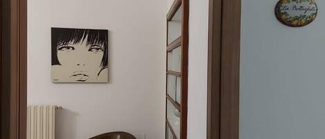 A doorway leading to a room with a radiator, a brown chair, and a wall-mounted picture.